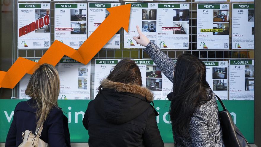 Imagen original: unas jóvenes observan los precios de unos pisos en el escaparate de una inmobiliaria