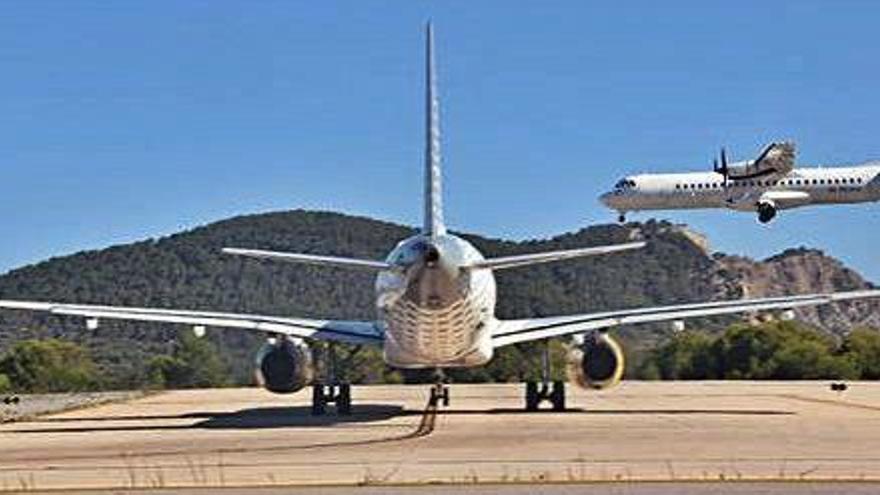 Un avión aterriza en Ibiza mientras otro espera en la cabecera de la pista.