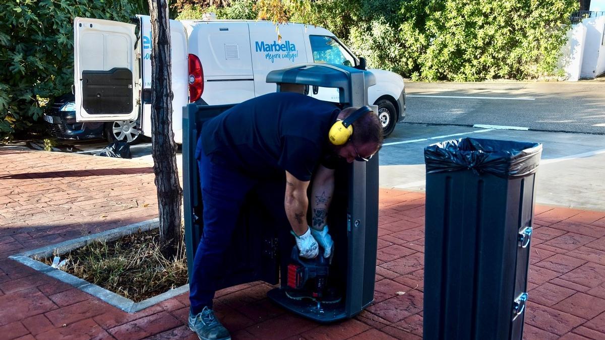 Un operario de Limpieza cambia una papelera en mal estado por otra nueva en una calle de Marbella.
