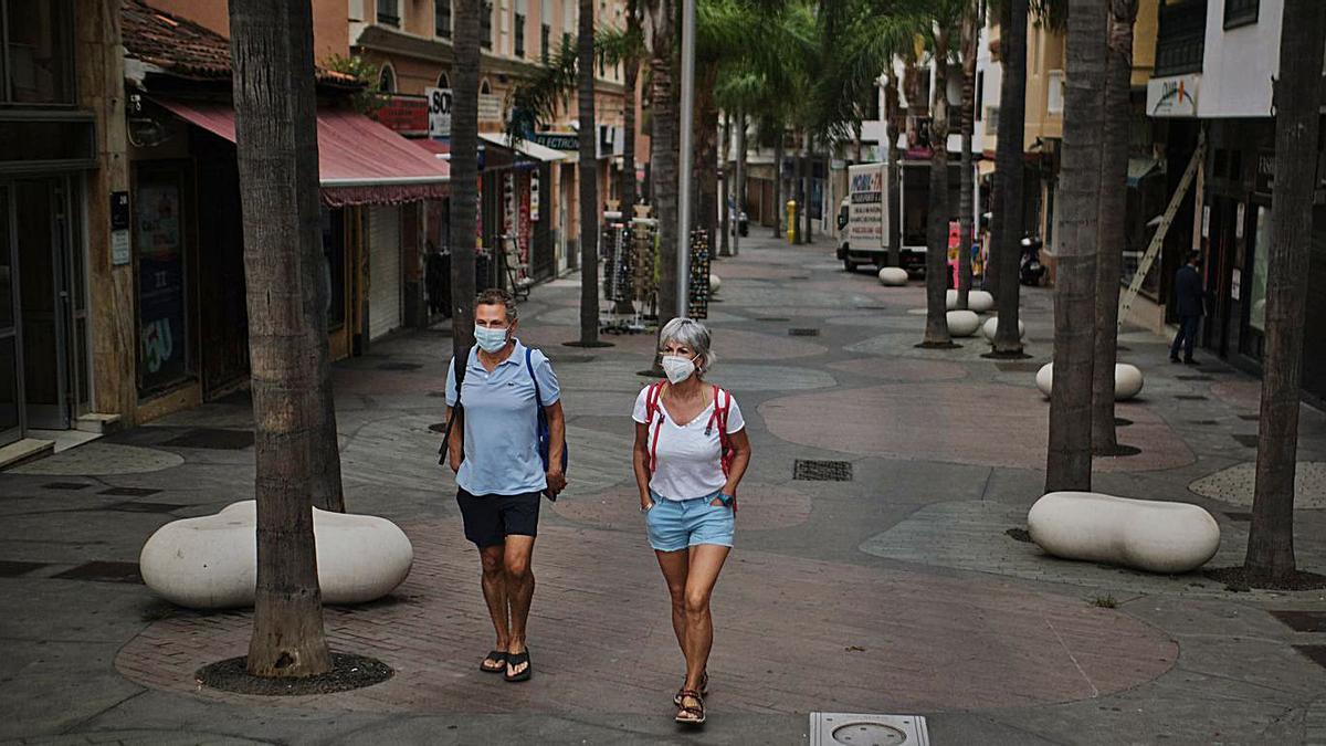 Dos turistas con mascarilla pasean por el centro de Puerto de la Cruz.