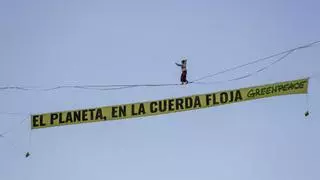 Una activista de Greenpeace camina sobre una cuerda a 30 metros de altura en Madrid