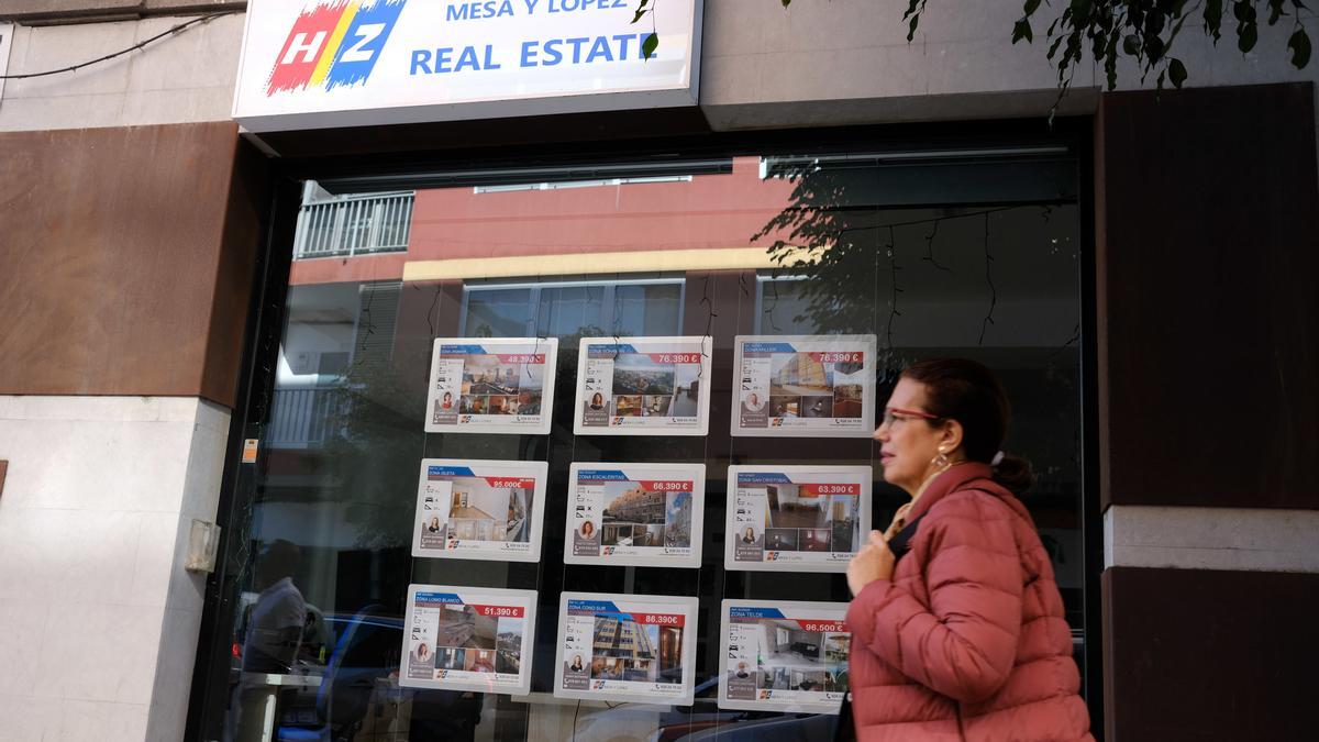 Una mujer pasea por delante de una agencia inmobiliaria de las Islas.