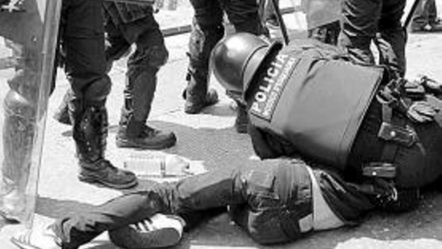 Un mosso d&#039;esquadra golpea a una persona durante una carga en la plaza de Cataluña, ayer por la mañana.