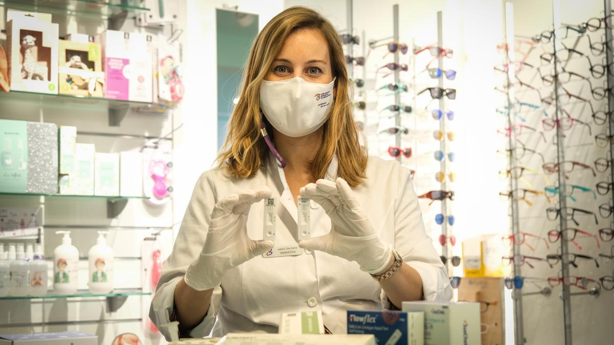 Una farmacéutica muestra unos test de antígenos, tras el mostrador de la farmacia de Cecilio Venegas.