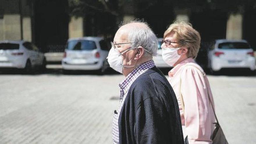 Un hombre y una mujer con mascarillas, por la calle.