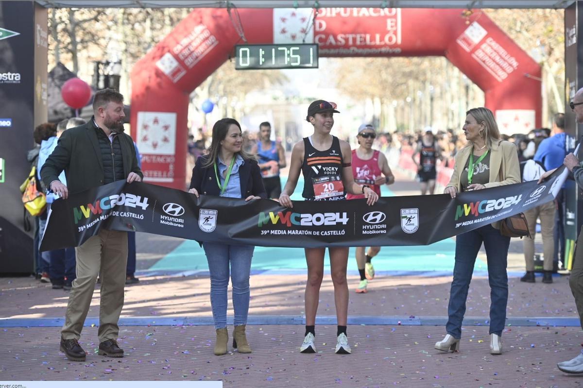 La triatleta de Bueu Natalia Castro posa en la línea de meta con las autoridades tras su triunfo en la Media Maratón de Castellón.