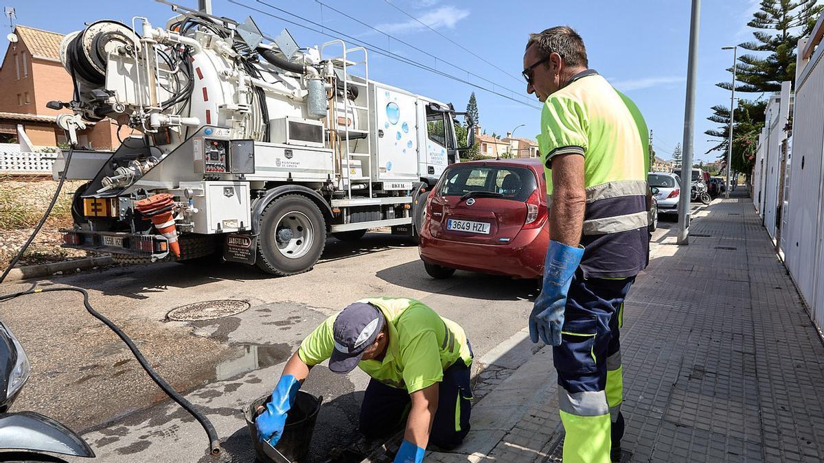 Dos operarios trabajan en la limpieza de imbornales en Gandia