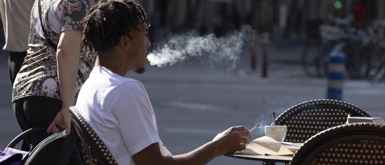 Un joven fuma en una terraza en Barcelona.