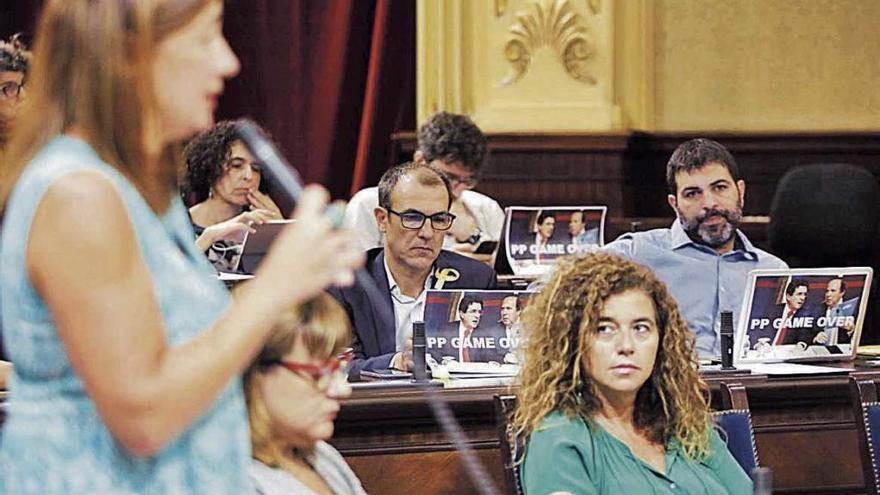 Armengol replica ayer a Company. Al fondo, diputados de Més muestran imágenes de Matas y Rodríguez.