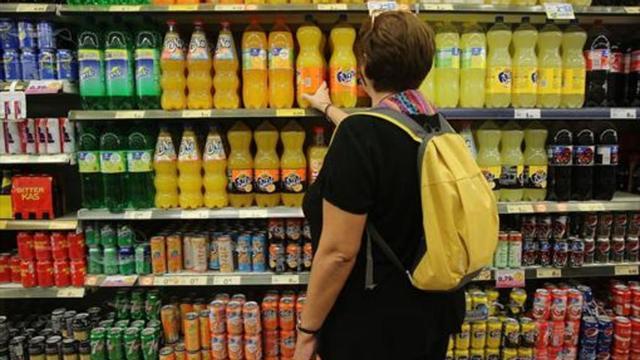 Una mujer ante las bebidas azucaradas de un supermercado.