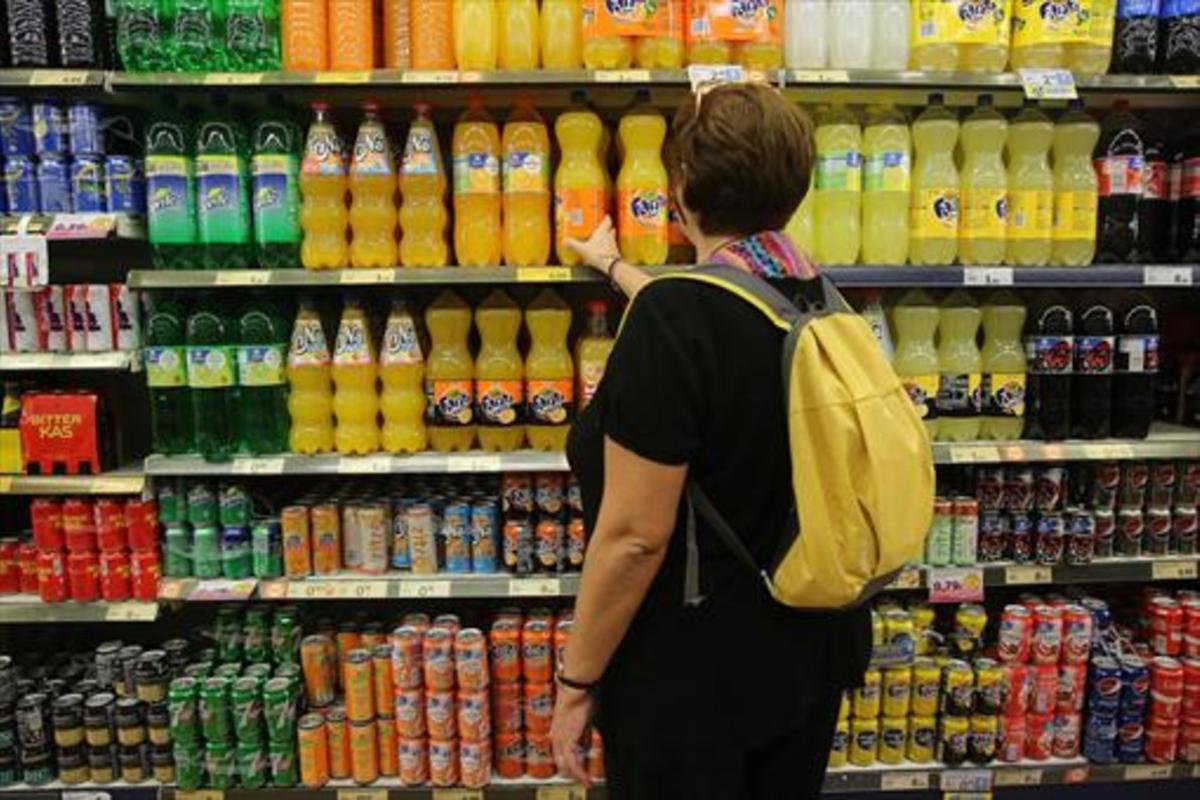 Una mujer ante las bebidas azucaradas de un supermercado.