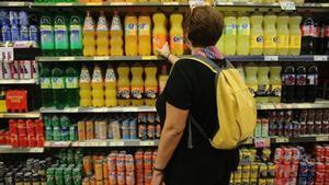 Una mujer ante las bebidas azucaradas de un supermercado.