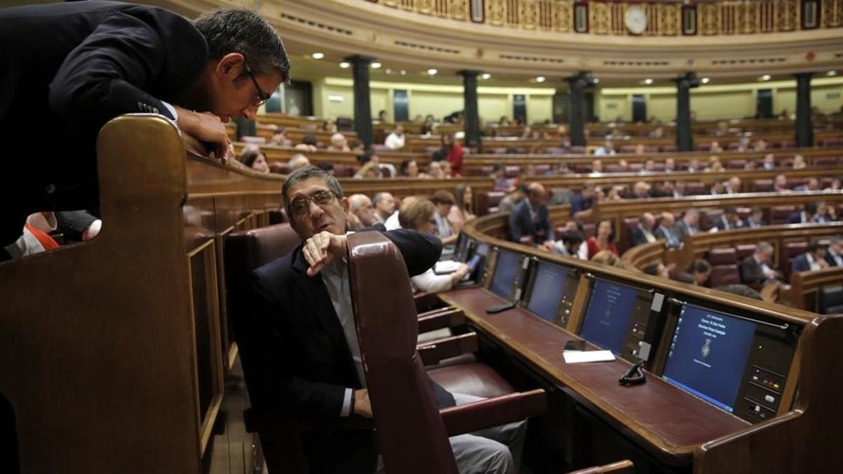 Patxi López y Eduardo Madina hablan ante la nueva butaca que ocupará Pedro Sánchez en el Congreso.