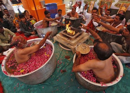 Sacerdotes hindúes se sientan en calderos de agua y hacen ofrendas en el frente de un fuego en el desempeño de la "Parjanya Varun Yagam", una oración especial por la lluvia, en la ciudad occidental india de Ahmedabad.