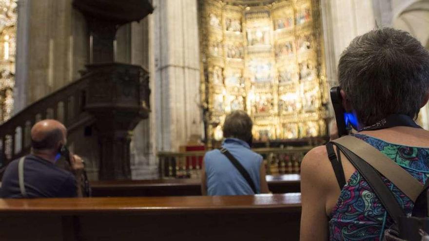 Varios turistas, ayer, siguen las explicaciones de la audioguía en el interior de la Catedral.