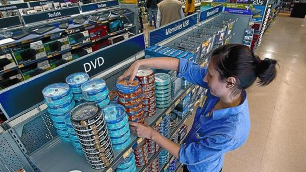 La empleada de una tienda de electrónica de Barcelona coloca discos en estanterías, ayer.