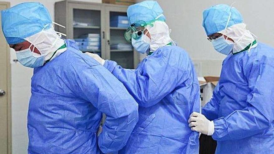 Tres metges s&#039;ajuden mútuament a posar-se la bata protectora en un hospital de la Xina.