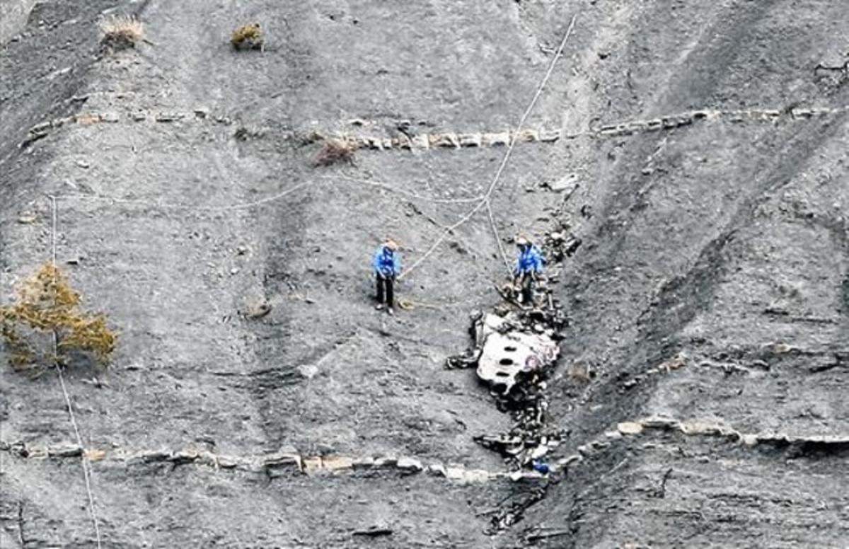 Un equip de rescat als Alps prova d’emportar-se’n una peça de l’avió estavellat de Germanwings, ahir.