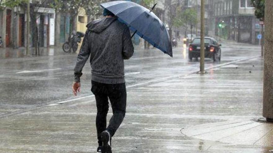 Un joven pasea solo bajo la lluvia.