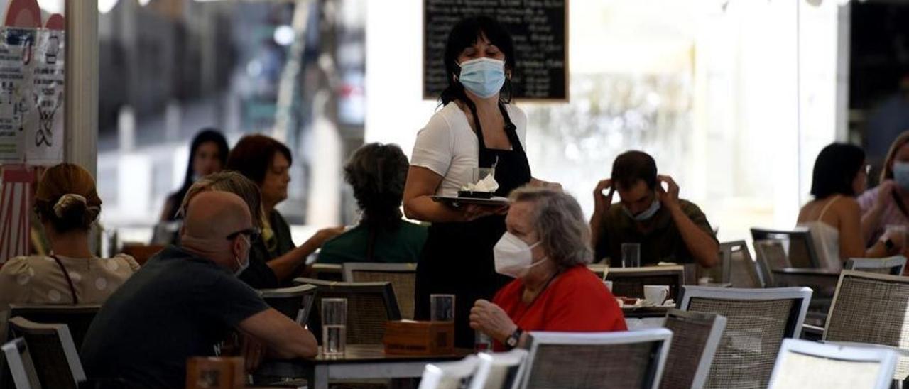 Una camarera atiende a los clientes de una terraza.