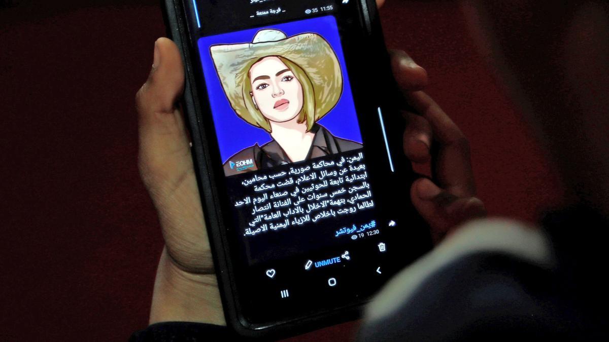 Sana'a (Yemen), 08/11/2021.- A Yemeni reads news on the screen of a mobile phone with a drawing depicting Yemeni model Entisar al-Hammadi after she has been given a five-year sentence in prison, in Sana'a, Yemen, 08 November 2021. A Houthi-run court in Sana'a has sentenced Yemeni model Entisar al-Hammadi, 20, to five years in prison over alleged charges of drug abuse and prostitution. Al-Hammadi was arrested in last February at a street in Sana'a. EFE/EPA/YAHYA ARHAB