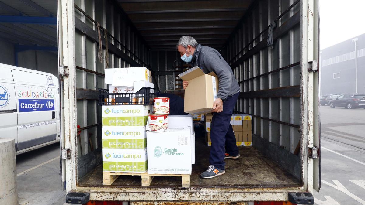 Un miembro de una asociación solidaria introduce comida en un camión con el fin de repartirla.