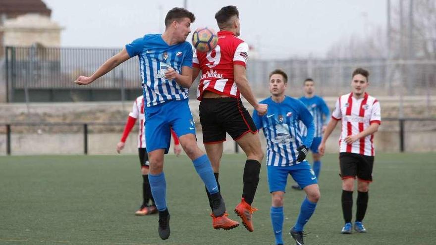 Un jugador de cada equipo salta para tratar de cabecear el esférico sin demasiado éxito.