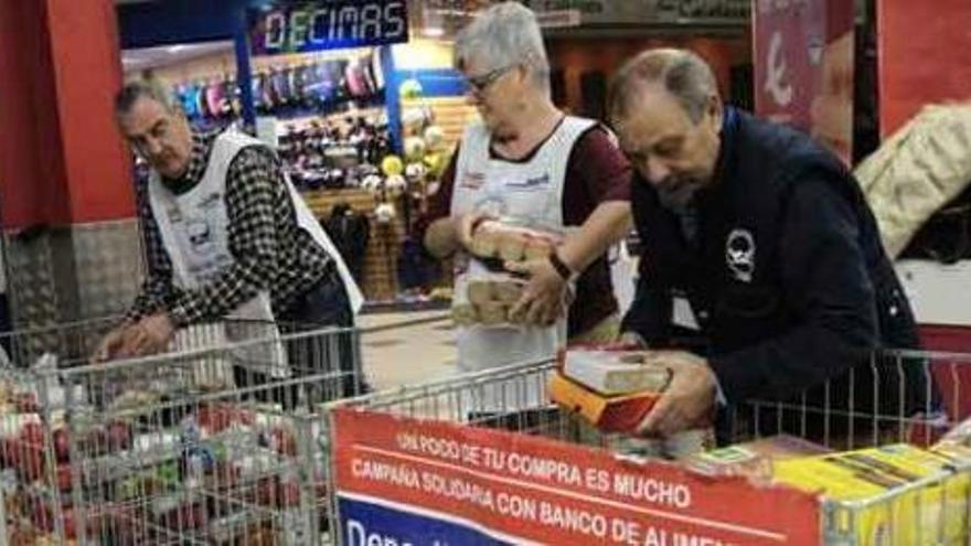 Tres voluntarios del Banco de Alimentos organizan los productos donados por los clientes en uno de los comercios participantes en la campaña.