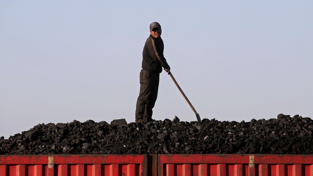Un trabajador sobe el cargamento de carbón que transporta un tren, en el centro de China.