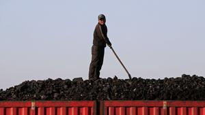 Un trabajador sobe el cargamento de carbón que transporta un tren, en el centro de China. 