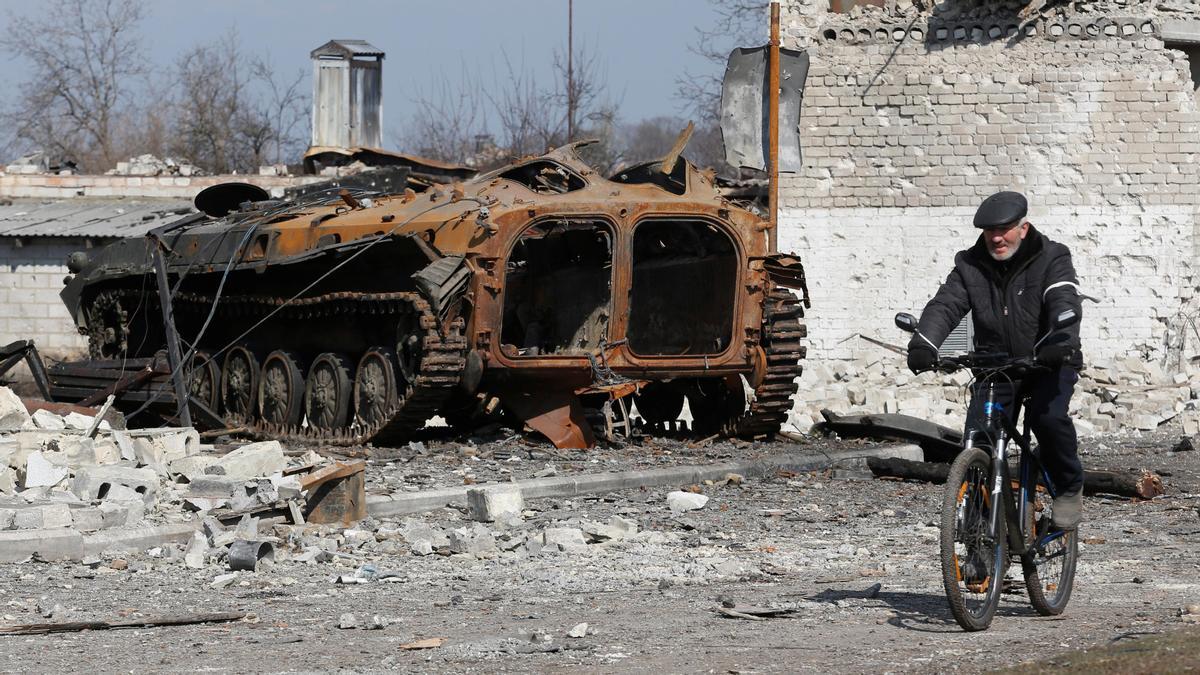 Un hombre pasa con su bici junto a un tanque destruido el la ciudad de Volnovakha.