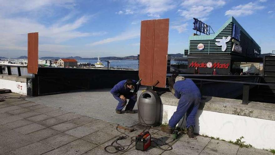 Operarios instalan planchas metálicas para reforzar la seguridad en la pasarela. // Ricardo Grobas