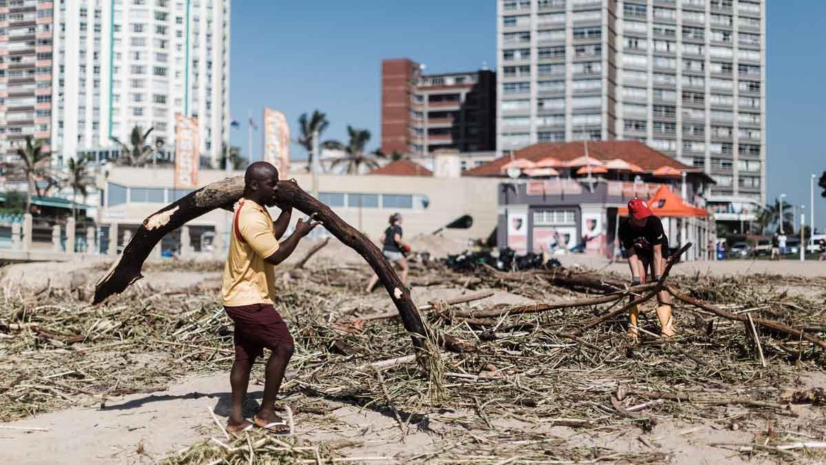 Voluntarios y miembros de los equipos de limpieza trabajan entre los escombros acumulados en la playa de North Beach tras las fuertes lluvias en Durban