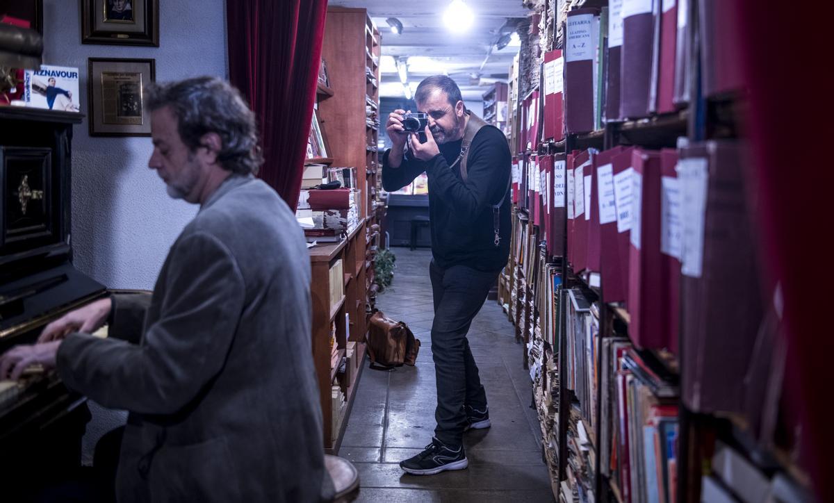 Esteve Vilarrúbies, cámara en mano, en el pasillo central de Casa Beethoven, nacida en 1883, mientras Jaume Doncós toca el piano del establecimiento.