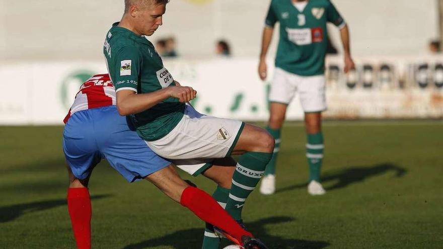 André Österholm, del Coruxo, protege el balón ante la presión de un jugador del Navalcarnero. // Ricardo Grobas