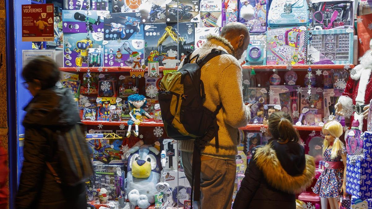Un padre y su hija frente a un escaparate de juguetes.