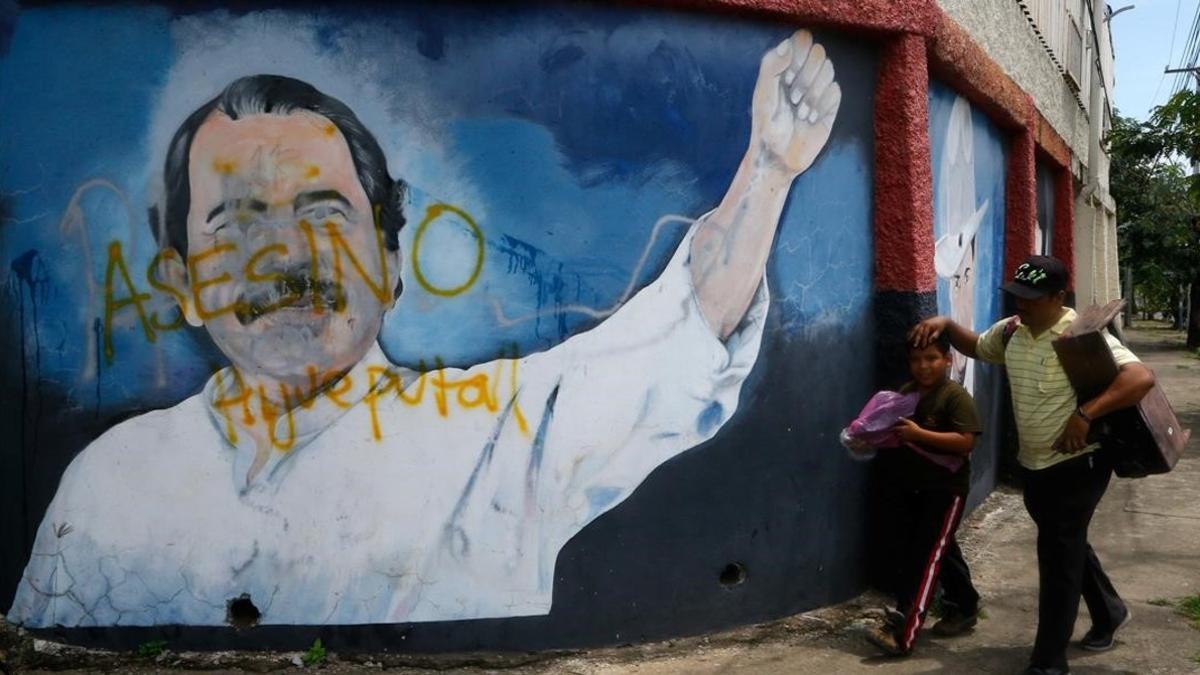 Dos personas pasan junto a un mural de Daniel Ortega en Managua.