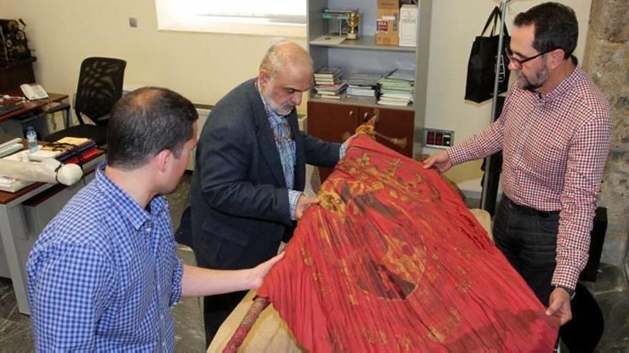 Pérez Adán (d), Antonio Pedreño (c) y otro trabajador del Archivo observan uno de los estandartes.