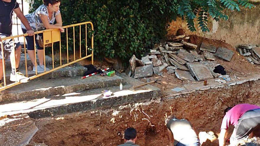 Dos personas observan a varios operarios durantre las labores de excavación de la supesta fosa.