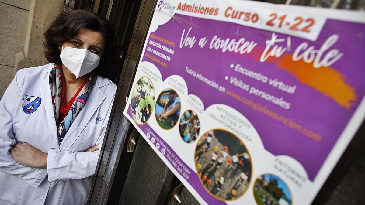 La directora de La Asunción, Elisa Díaz, ayer, a la entrada del centro, junto a un cartel que detalla el proceso de admisión de alumnos para el próximo curso. | Ángel González