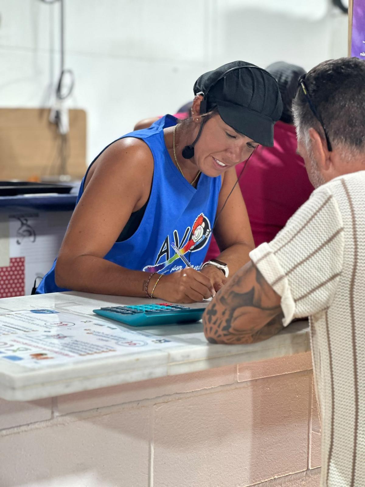 Una voluntaria de AVOI atiende a un cliente en la Feria de Málaga.