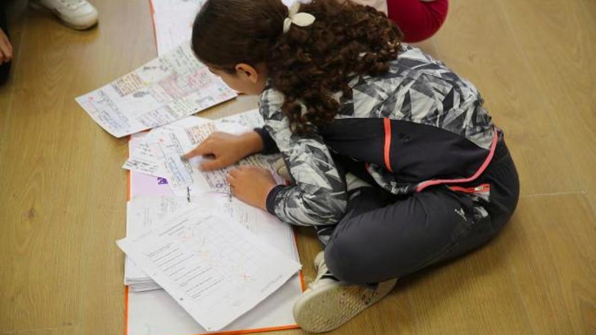 Una alumna de primaria, revisa sus deberes antes de entrar en clase.