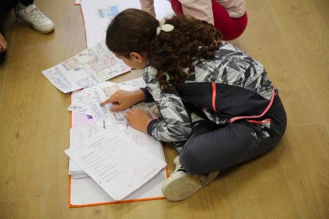 Una alumna de primaria, revisa sus deberes antes de entrar en clase.