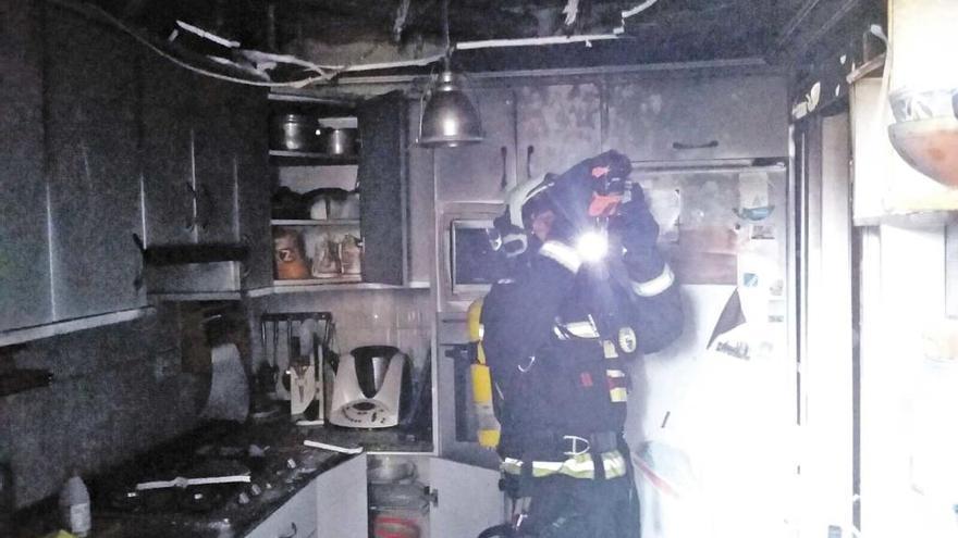 Un bombero inspecciona la cocina de la vivienda donde se produjo la explosión.