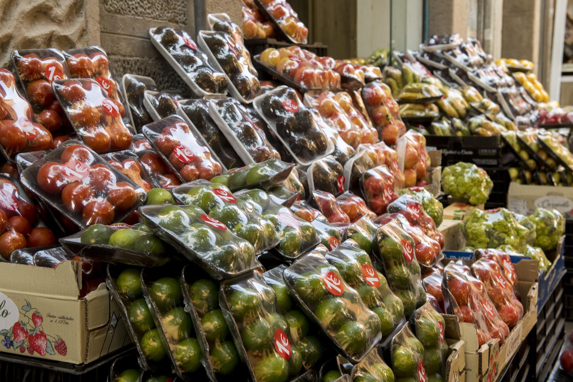 Verduras y frutas envueltas en embases de plástico en una tienda.