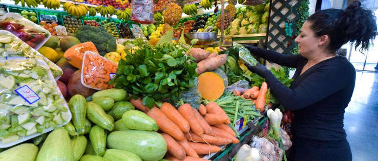 Una mujer, en el puesto de frutas y verduras de un mercado.