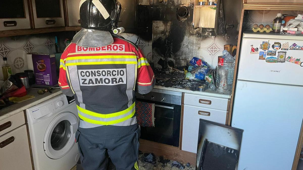 Un bombero ante el foco del fuego, en la cocina la vivienda donde se originó.