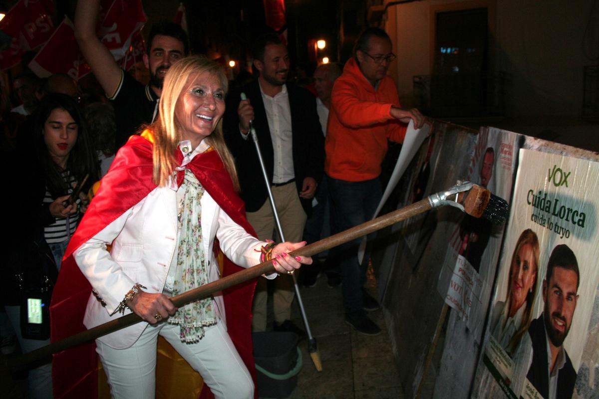 La candidata de Vox a la Alcaldía, Carmen Menduiña, con una bandera de España como capa, pegaba el primer cartel de la campaña electoral en la Plaza de la Estrella.