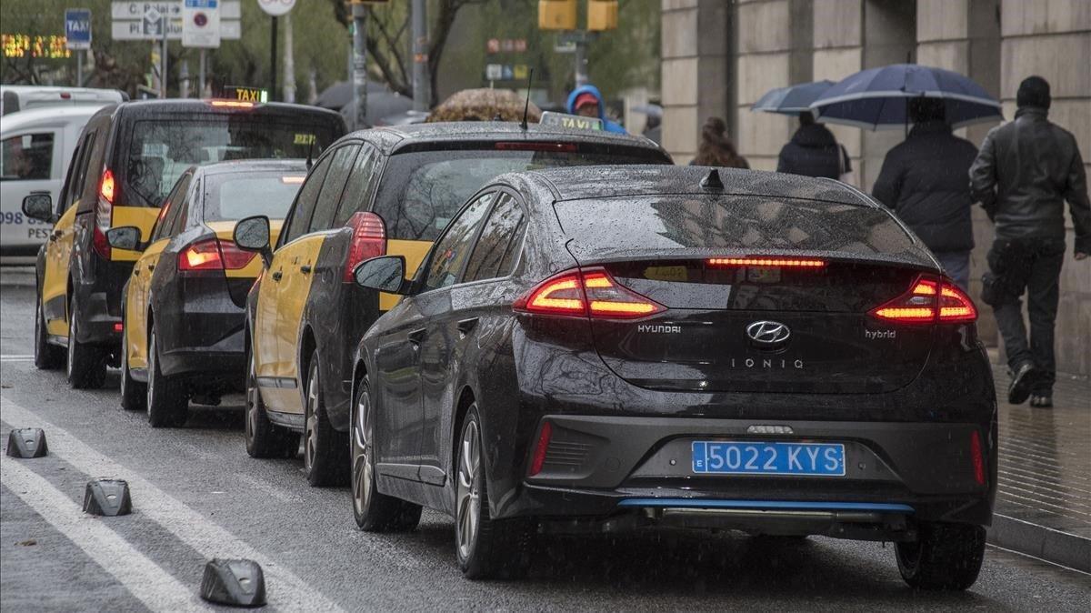 Taxis y un vehículo VTC, circulando juntos por el carril taxi, el viernes, en Barcelona.