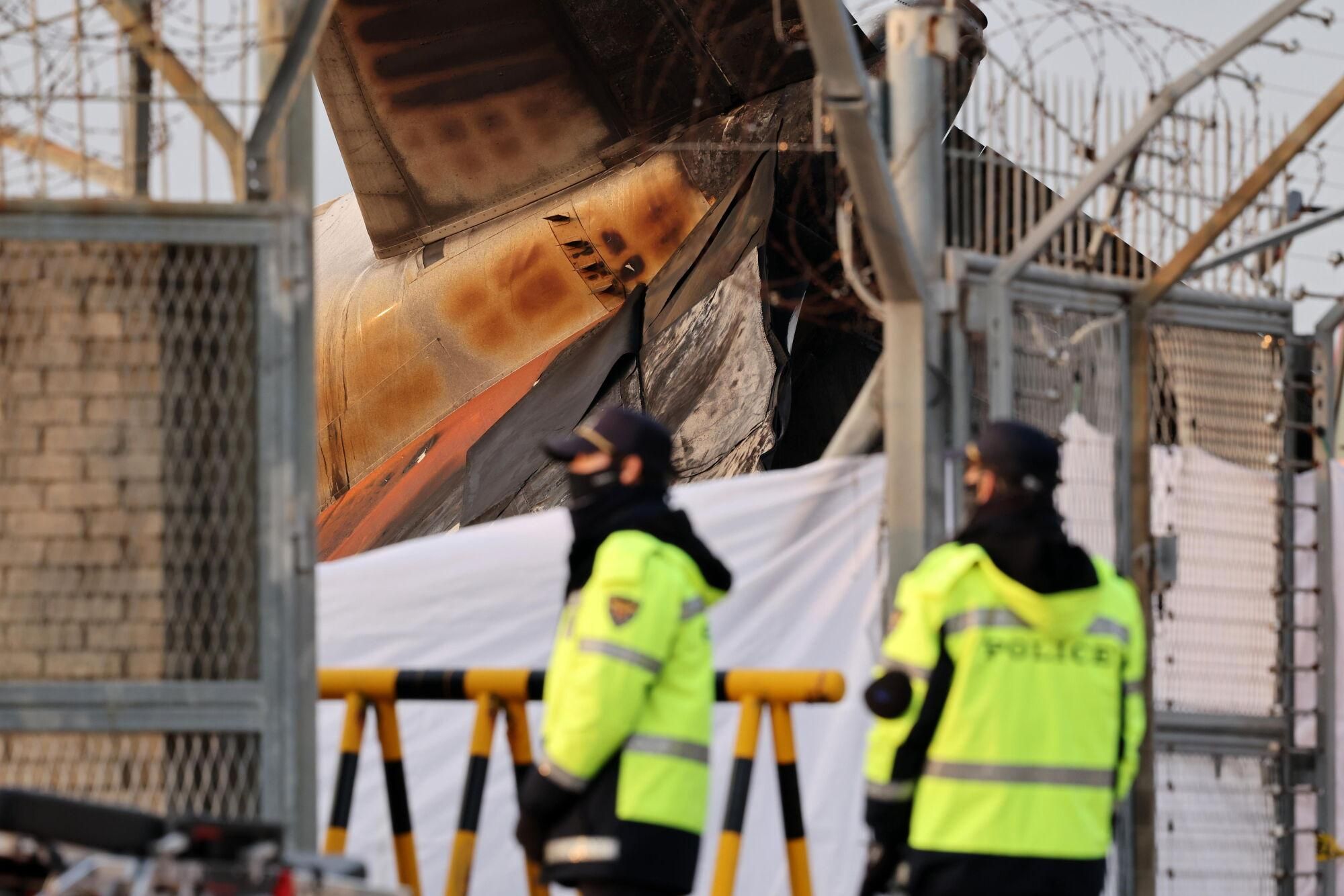 Muan (South Korea), 29/12/2024.- Police forces stand near the wreckage of the Jeju Air aircraft at Muan International Airport in Muan, 288 kilometers southwest of Seoul, South Korea, 29 December 2024. According to the National Fire Agency, a passenger jet carrying 181 people erupted in flames after going off the runway at an airport in South Korea's southwestern county of Muan on 29 December, leaving at least 62 people dead. (Corea del Sur, Seúl) EFE/EPA/HAN MYUNG-GU